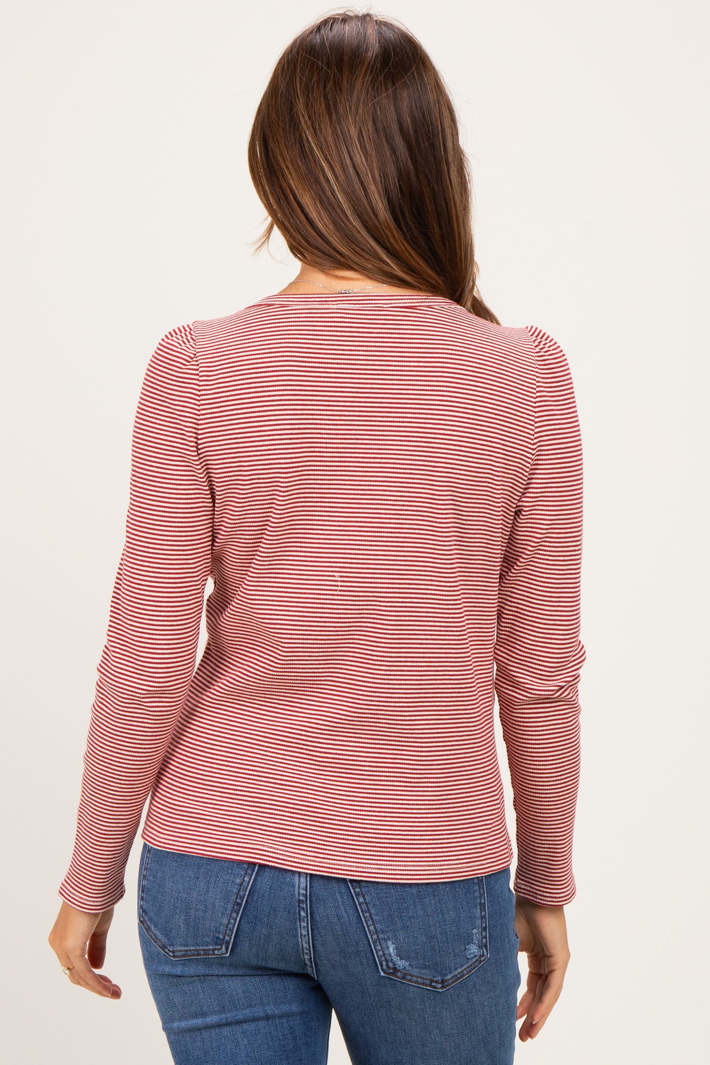 woman wearing a red and white striped long sleeve maternity top, viewed from the back with casual blue jeans