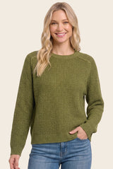 woman wearing a green textured knit sweater with a crew neckline and long sleeves, smiling