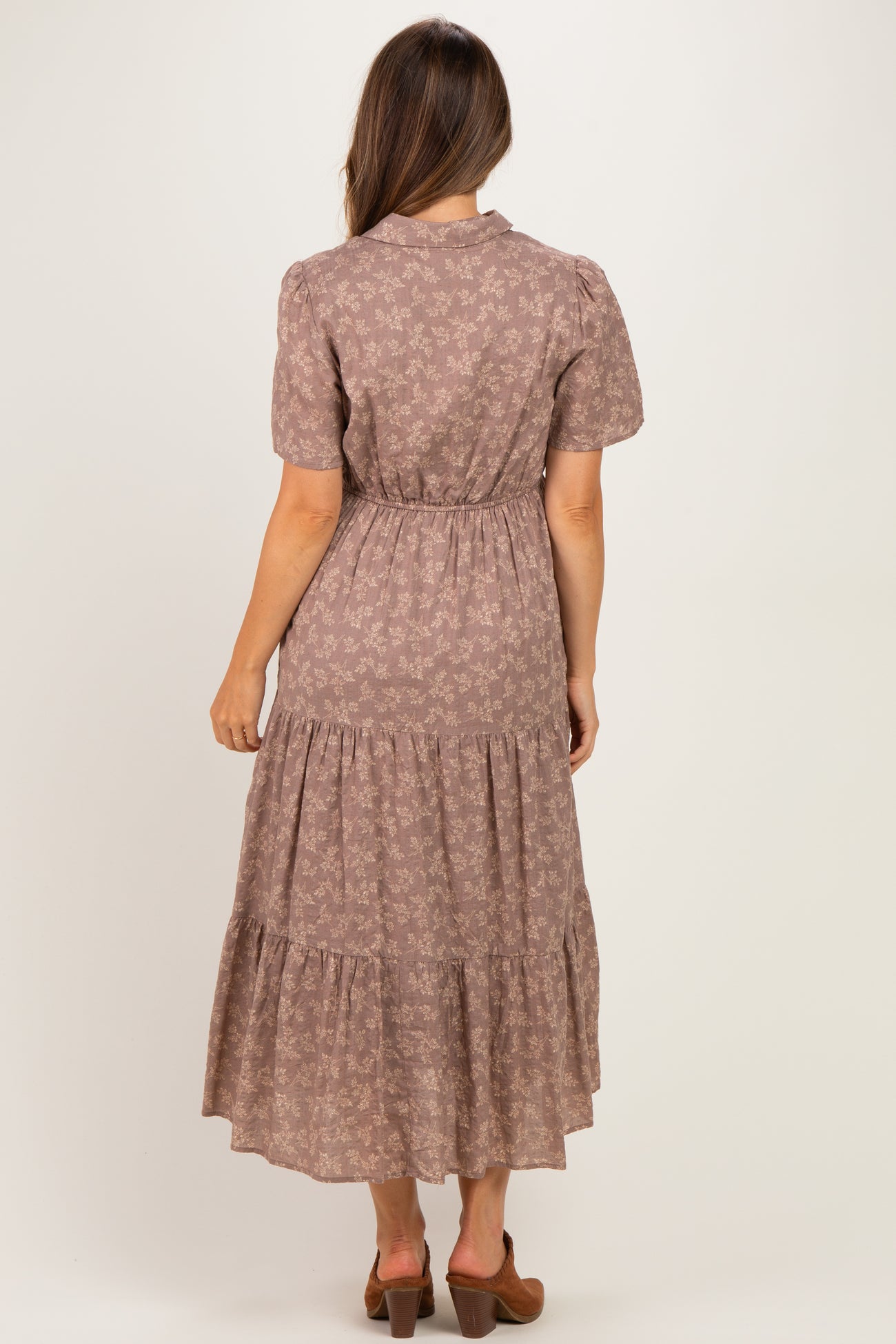 woman wearing a brown floral maternity maxi dress with puff sleeves and a tiered skirt, showing her back