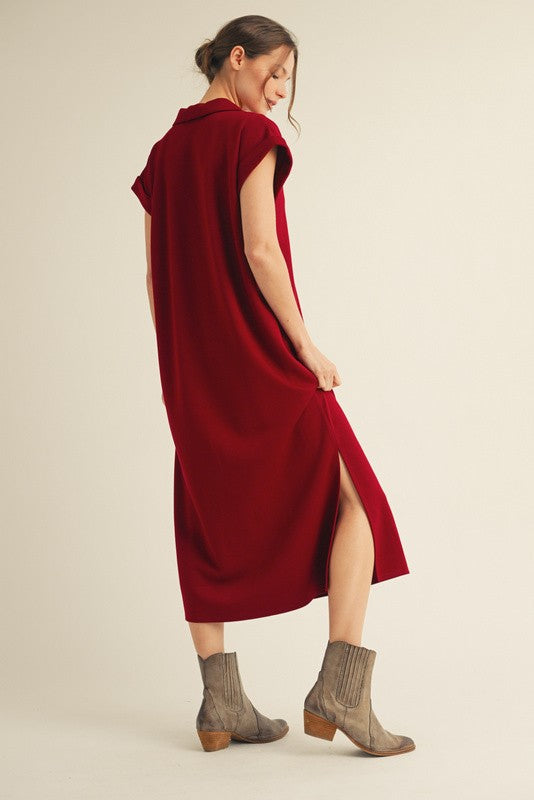 woman wearing a maroon midi dress with short sleeves and side slits, paired with grey ankle boots