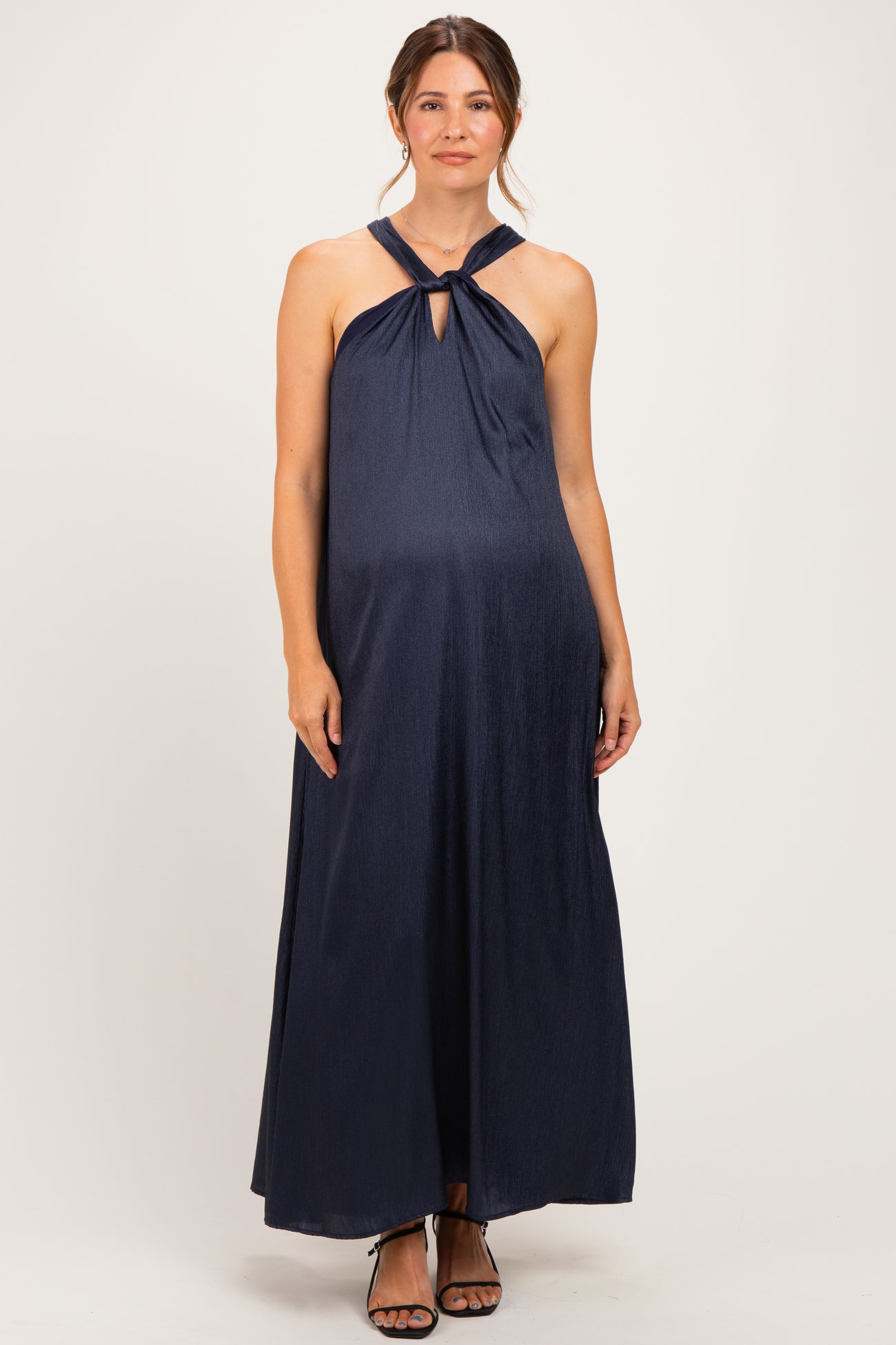 woman wearing a navy blue halter neck maternity maxi dress with a keyhole detail and visible baby bump