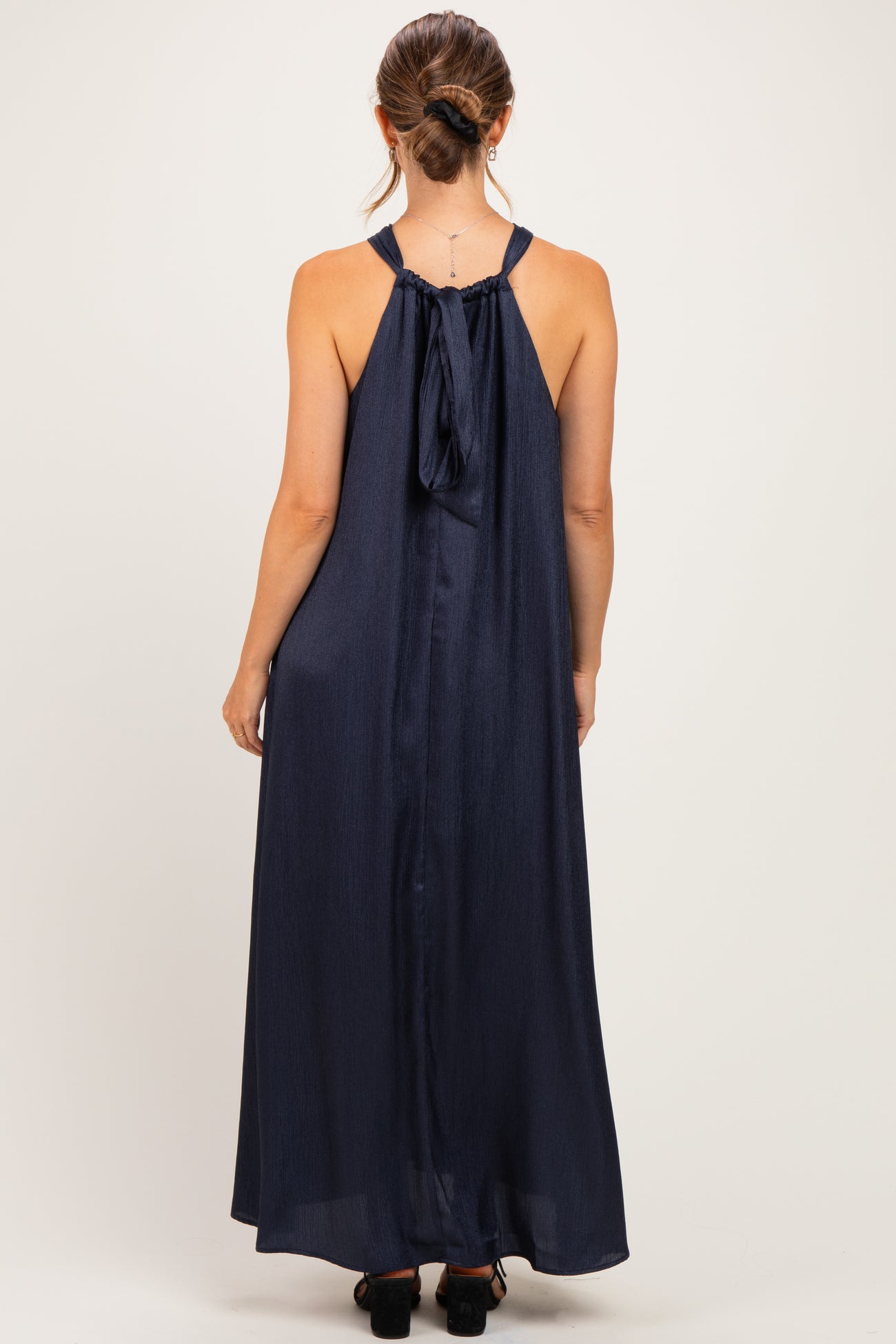 woman wearing a navy blue sleeveless maternity maxi dress with a bow detail at the back
