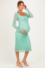 woman wearing a mint green lace maternity dress and holding her baby bump