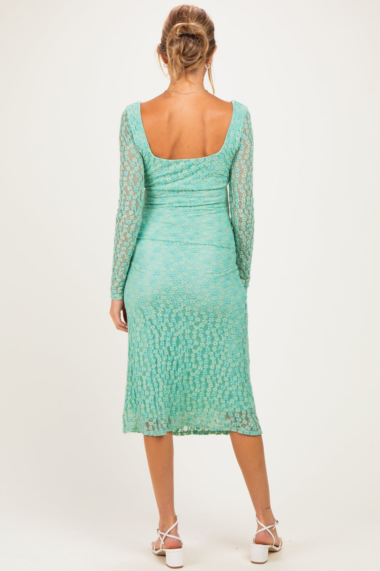 woman wearing a light teal long sleeve maternity dress with a fitted silhouette and lace detail