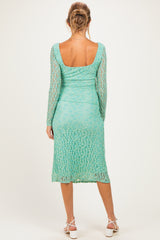 woman wearing a light teal long sleeve maternity dress with a fitted silhouette and lace detail