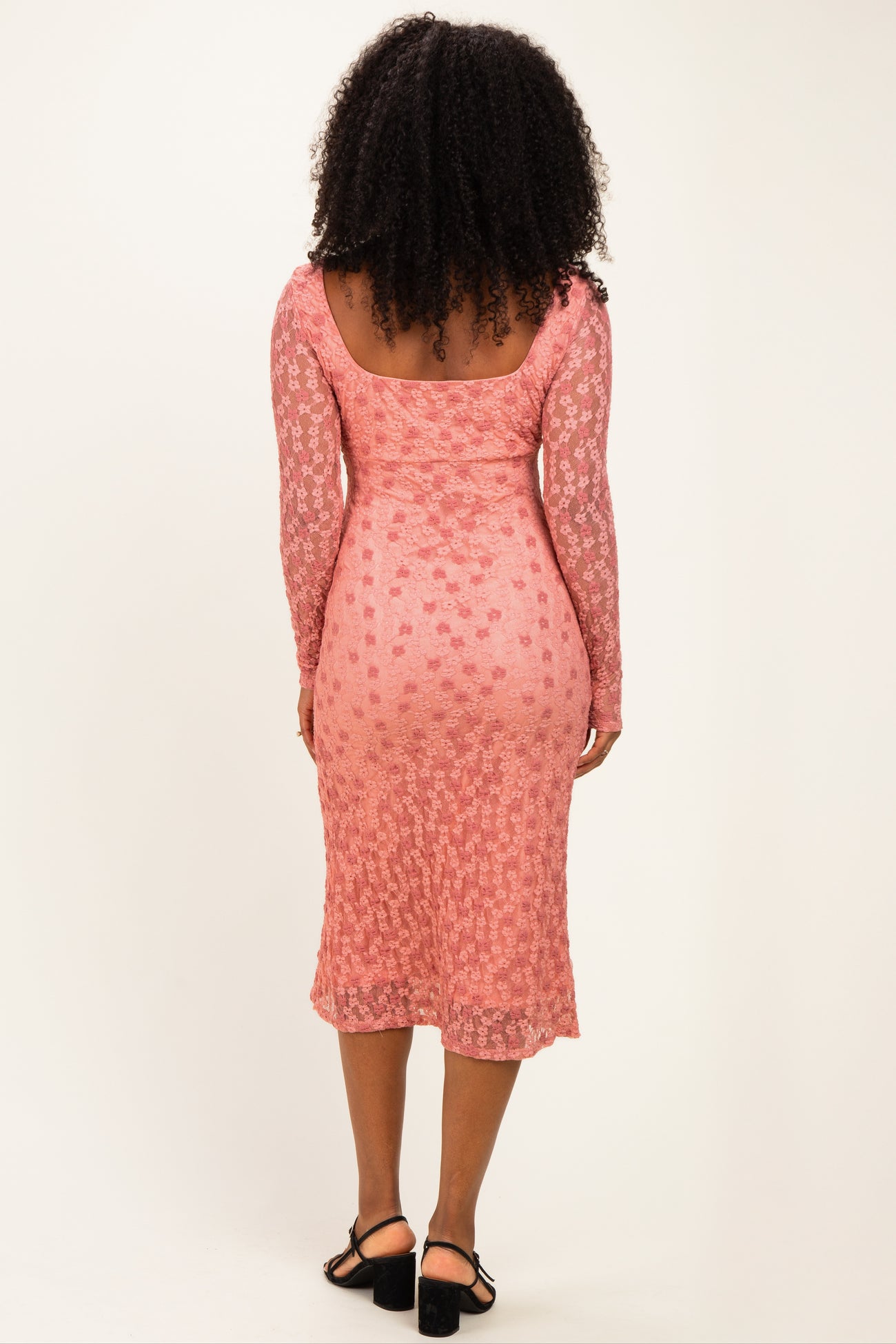 woman wearing a pink long sleeve lace midi dress with floral patterns and a fitted silhouette, seen from the back