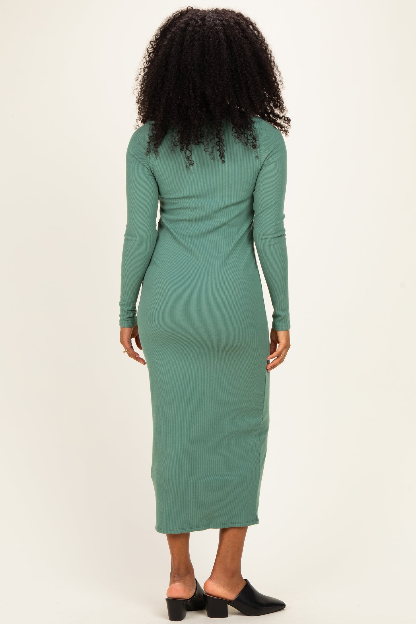 woman wearing a long sleeve green maxi dress with a fitted silhouette and side slit, seen from the back