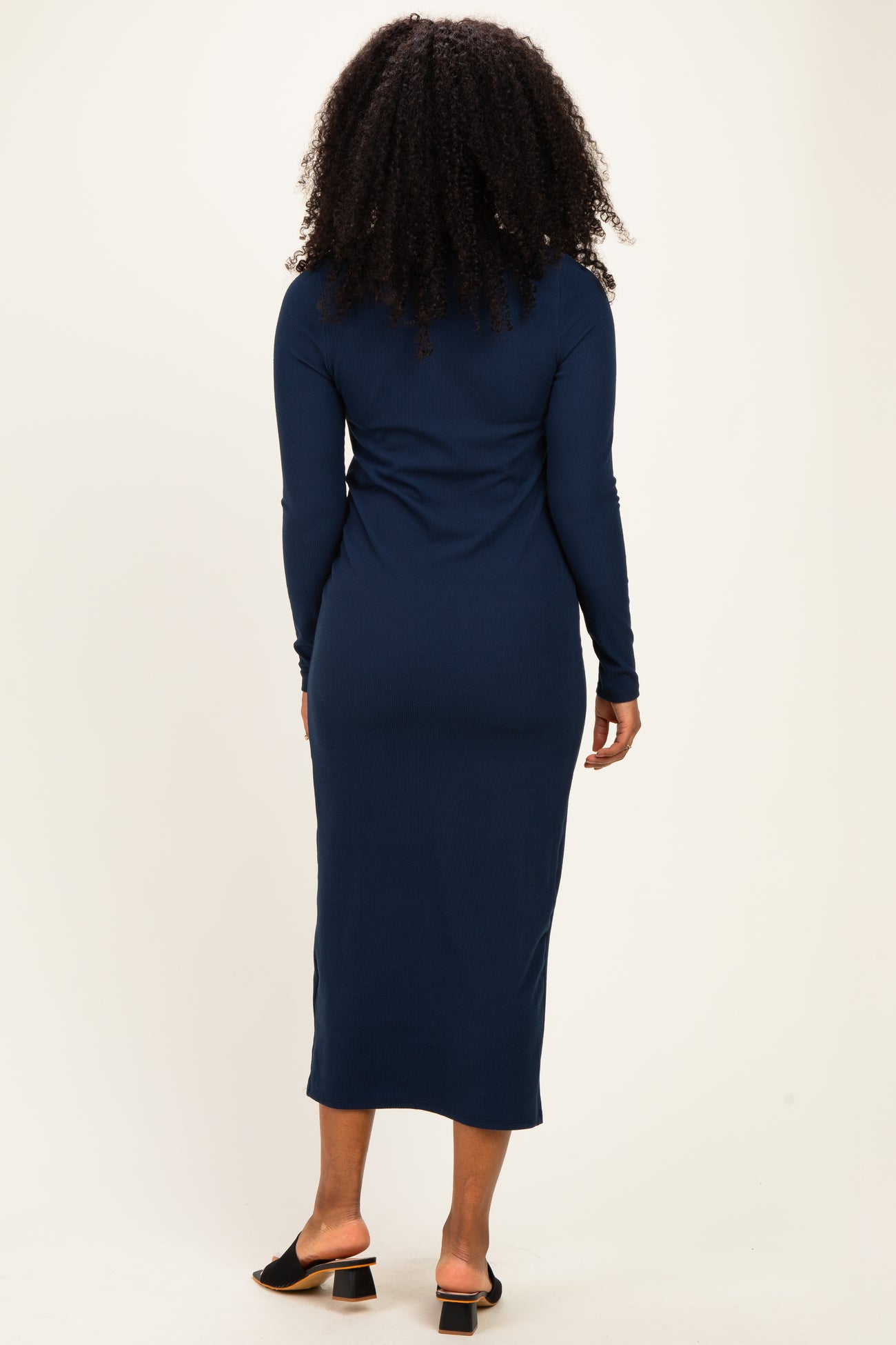 woman wearing a long sleeve navy blue ribbed midi dress, viewed from the back