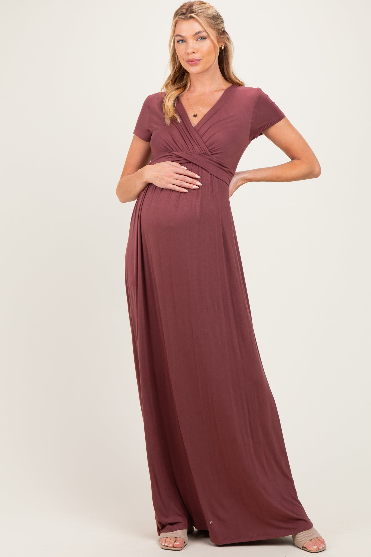 woman wearing a burgundy short sleeve maternity maxi dress and holding her baby bump