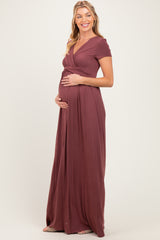 woman wearing a burgundy maternity maxi dress with a v-neck and short sleeves, holding her baby bump