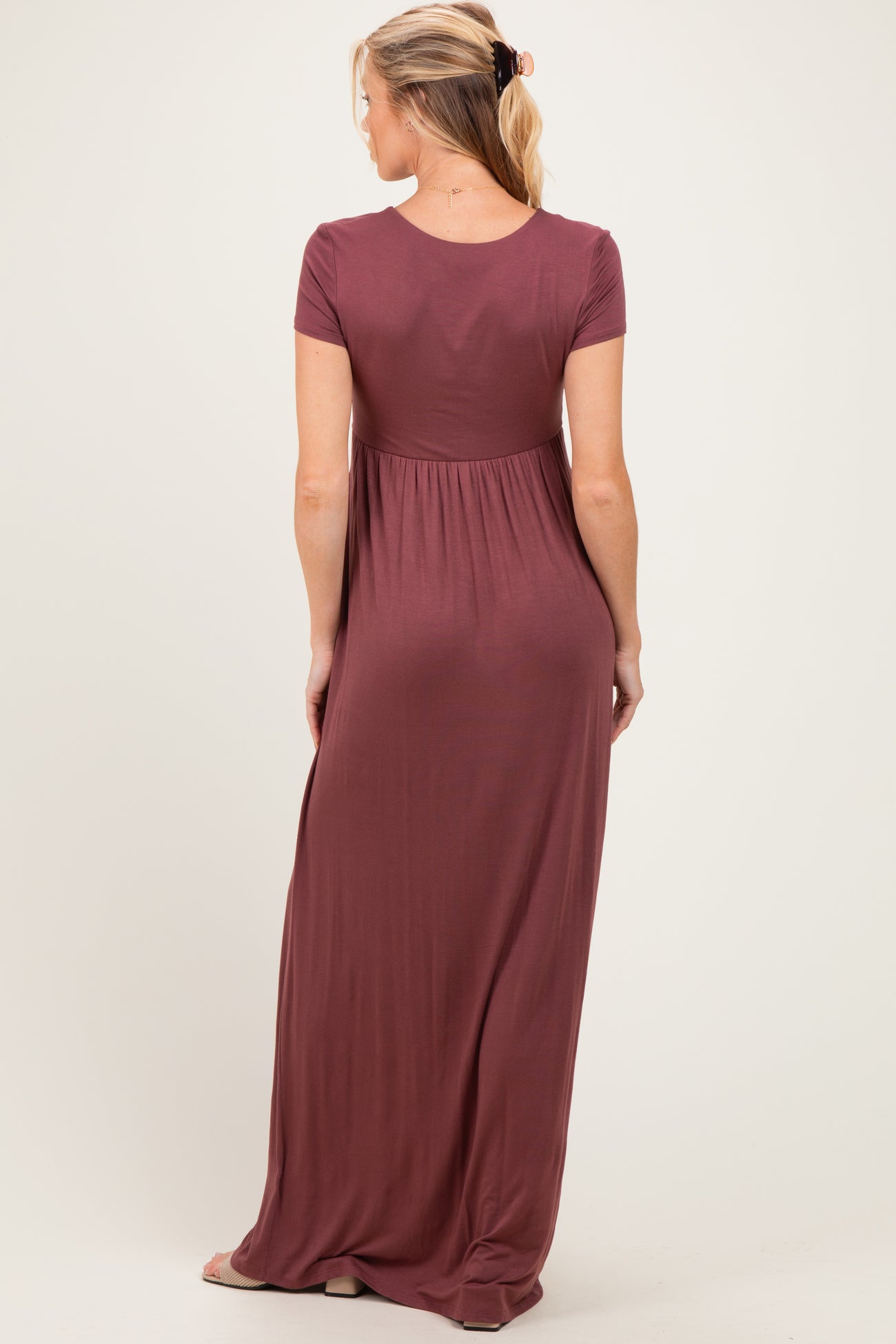 woman wearing a burgundy short sleeve maternity maxi dress, showing the back and gathered waist detail