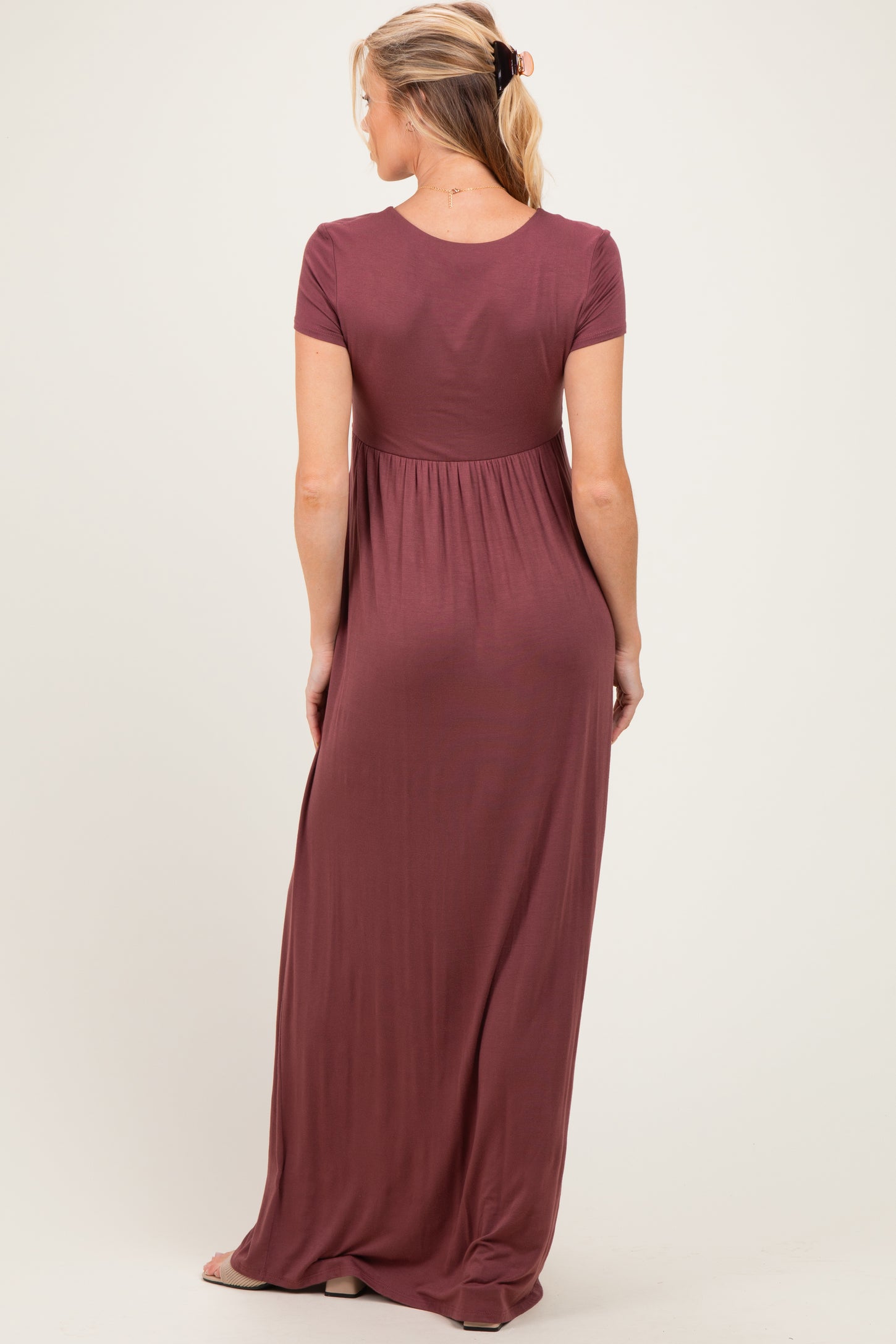 woman wearing a burgundy short sleeve maternity maxi dress, showing the back and gathered waist detail
