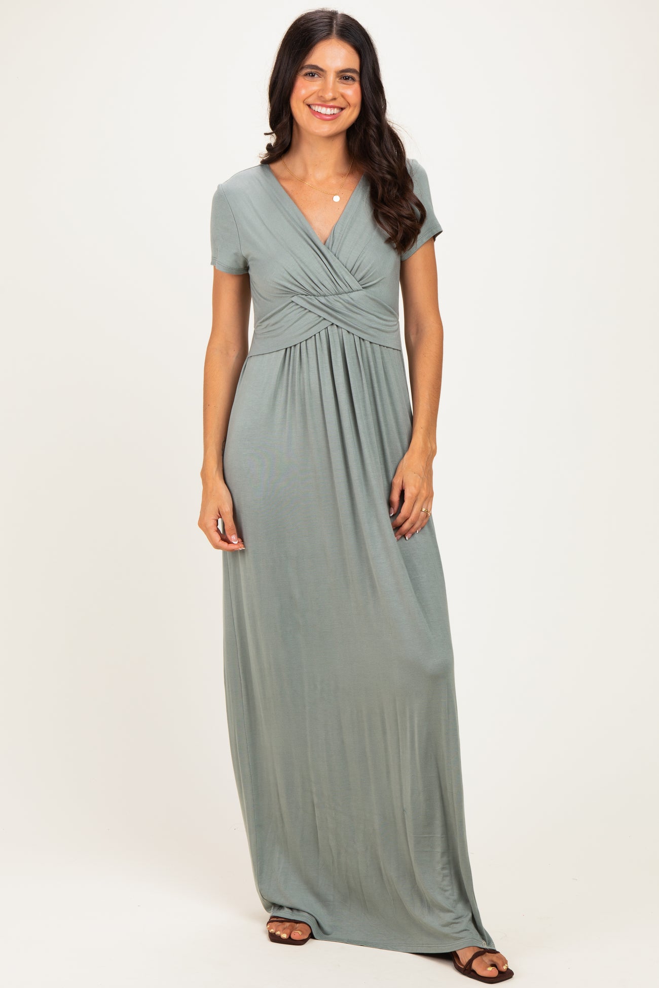 woman wearing a sage green short sleeve maxi dress with a twisted front detail and a relaxed fit