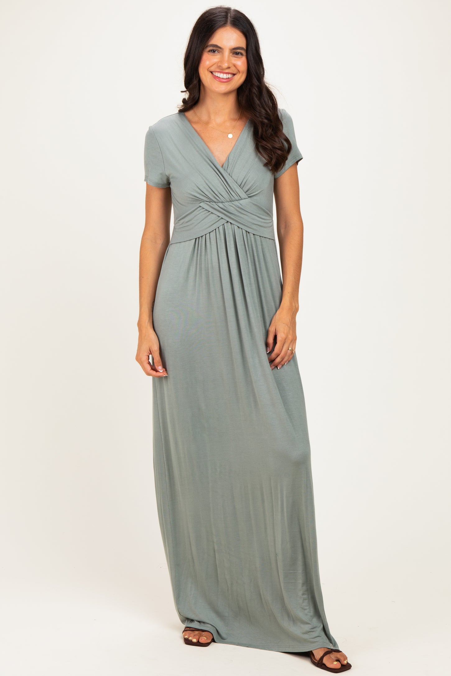 woman wearing a sage green short sleeve maxi dress with a twisted front detail and a relaxed fit
