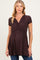 woman wearing a brown short sleeve maternity top with a crossover wrap design and a visible baby bump