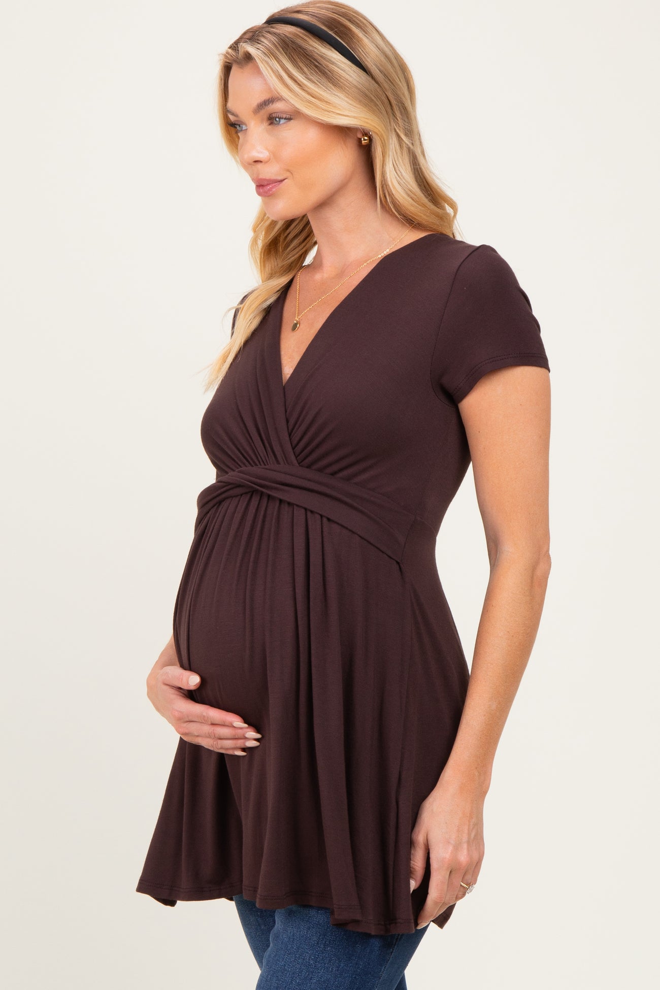 woman wearing a brown short sleeve maternity dress and holding her baby bump