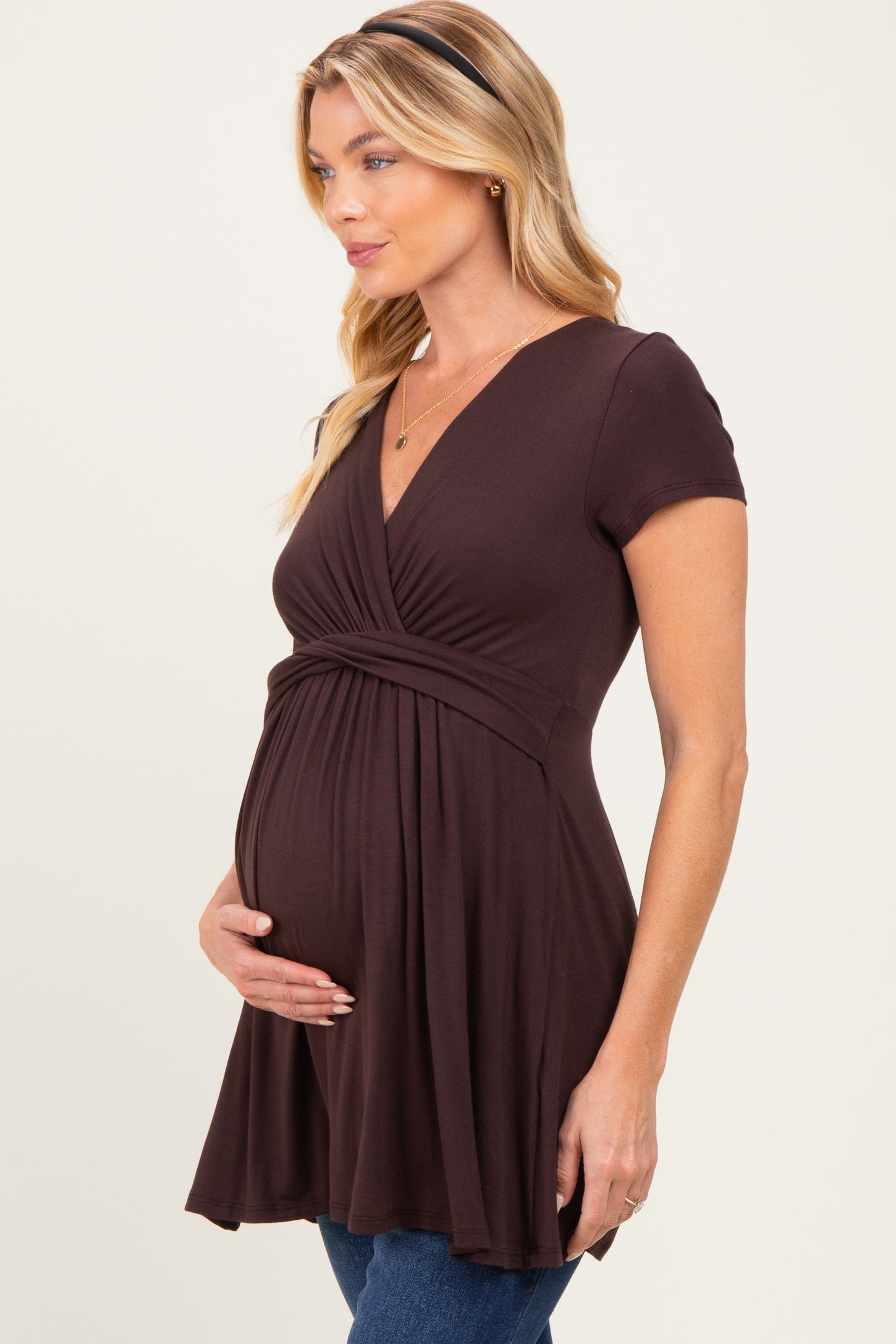 woman wearing a brown short sleeve maternity dress and holding her baby bump
