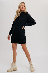 woman wearing a black knit hooded sweater dress with a relaxed fit and paired with beige lace-up boots