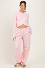 woman wearing a light pink long sleeve maternity top with a knot detail and matching relaxed fit pants