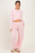 woman wearing a light pink long sleeve maternity top with a knot detail and matching relaxed fit pants