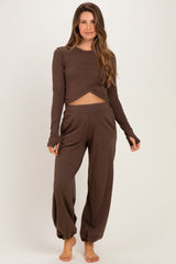 woman wearing a brown long sleeve crop top and matching pants, styled for maternity wear
