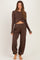 woman wearing a brown long sleeve crop top and matching pants, styled for maternity wear