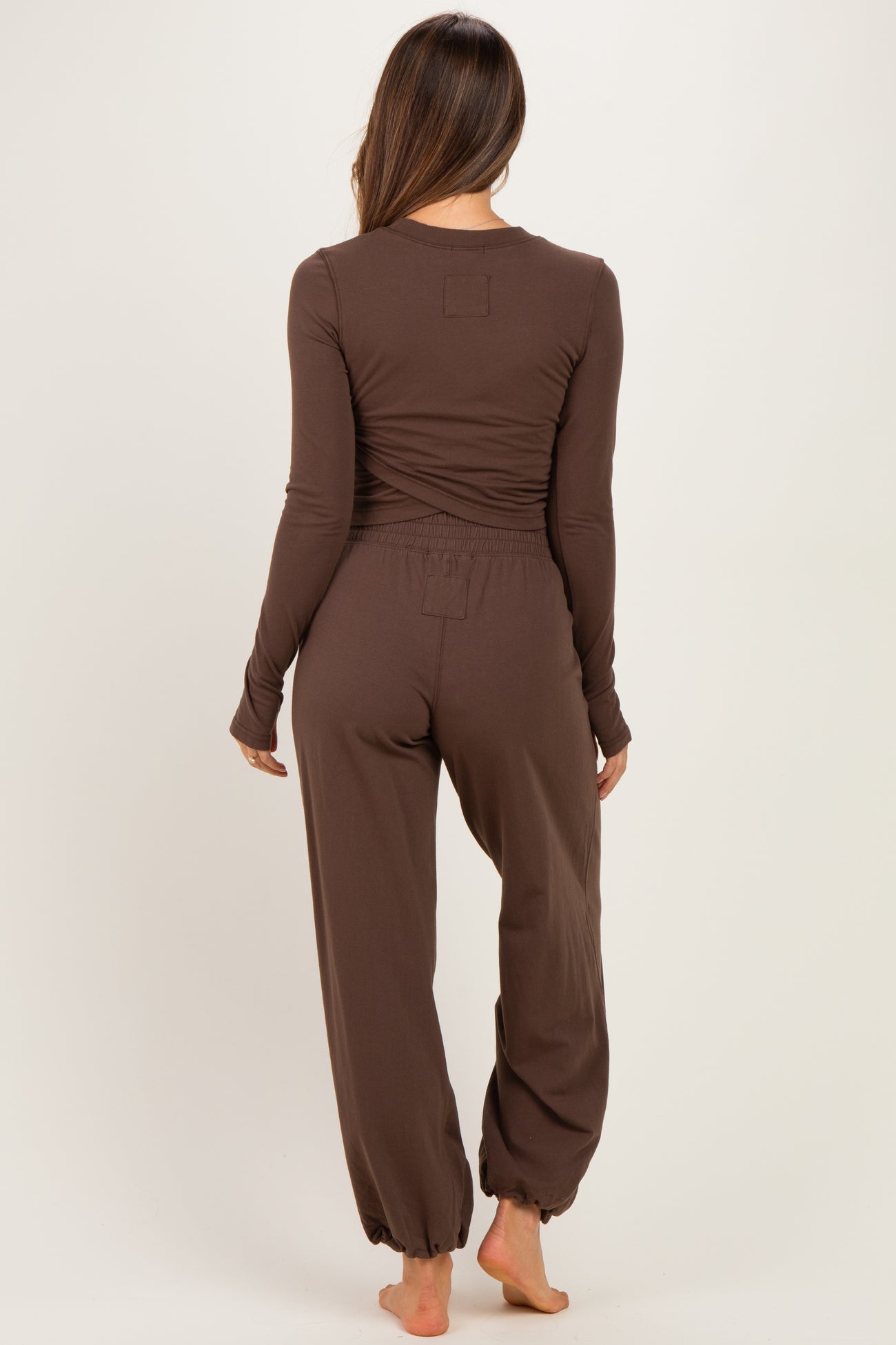 woman wearing a brown long sleeve maternity loungewear set with cinched pants and a relaxed fit