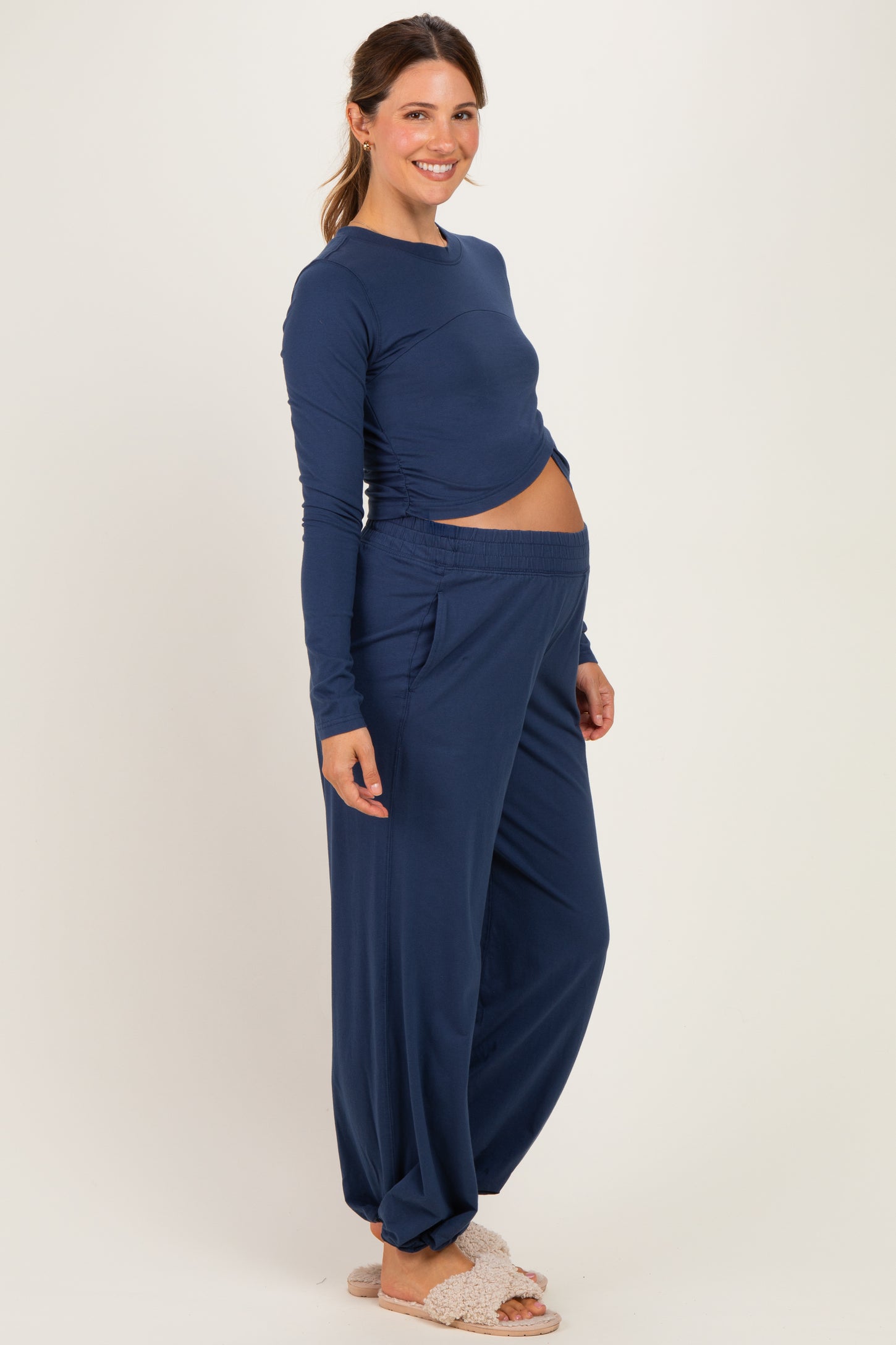 woman wearing a navy blue long sleeve maternity top and matching wide-leg maternity pants, showing her baby bump