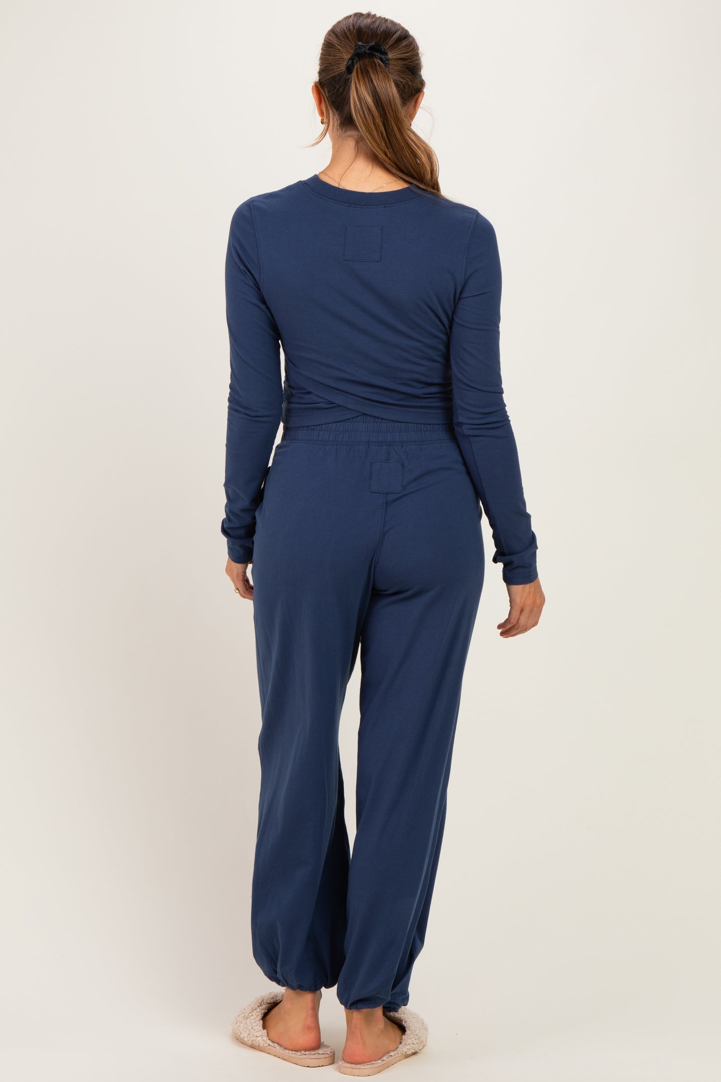 woman wearing a dark blue long sleeve maternity top and matching pants, showing a relaxed fit from the back