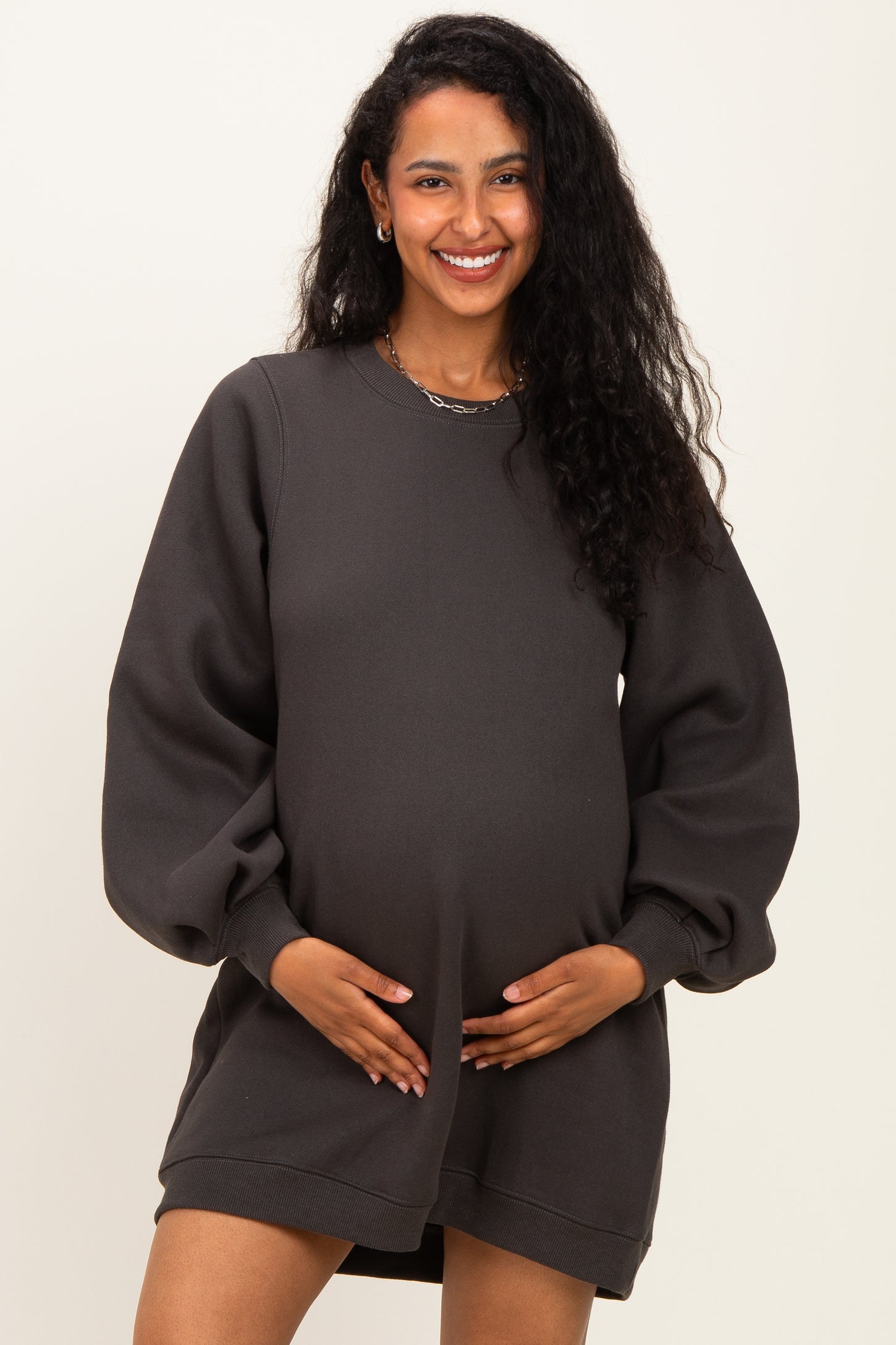 woman wearing a charcoal gray maternity sweatshirt dress and holding her baby bump