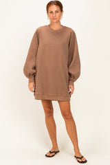 woman wearing a brown oversized sweatshirt dress with balloon sleeves and standing in flip flops