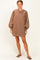 woman wearing a brown oversized sweatshirt dress with balloon sleeves and standing in flip flops