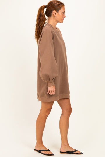 woman wearing a brown oversized sweatshirt dress with balloon sleeves and a relaxed fit