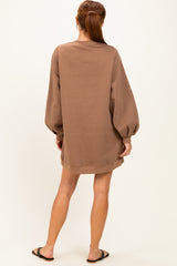 woman wearing a brown oversized sweatshirt dress with balloon sleeves and a relaxed fit, viewed from the back