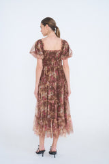 woman wearing a brown floral midi dress with puff sleeves and tiered ruffle hem, shown from the back