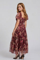 woman wearing a floral print maxi dress with puff sleeves and a tiered skirt, posing from the back