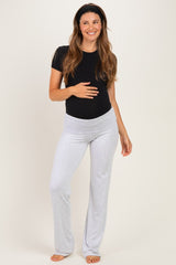 woman wearing a black short sleeve maternity top and gray maternity pants, with her baby bump visible