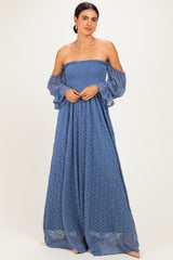 woman wearing a blue off-the-shoulder maxi dress with lace details and flared sleeves