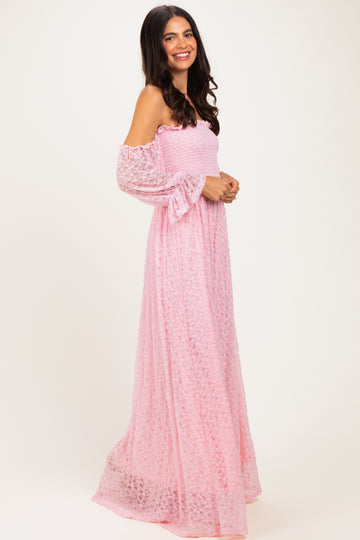 woman wearing a pink off-the-shoulder maxi dress with long sleeves and a smocked bodice