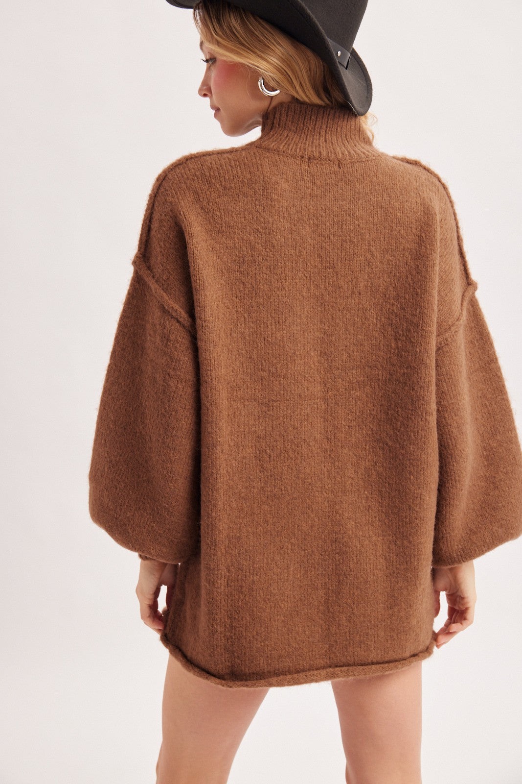 woman wearing a brown oversized sweater with a high collar and balloon sleeves, viewed from the back