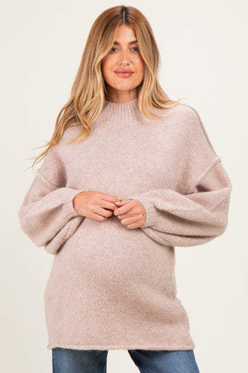 woman wearing a soft beige oversized maternity sweater with balloon sleeves and a relaxed fit, showing her baby bump