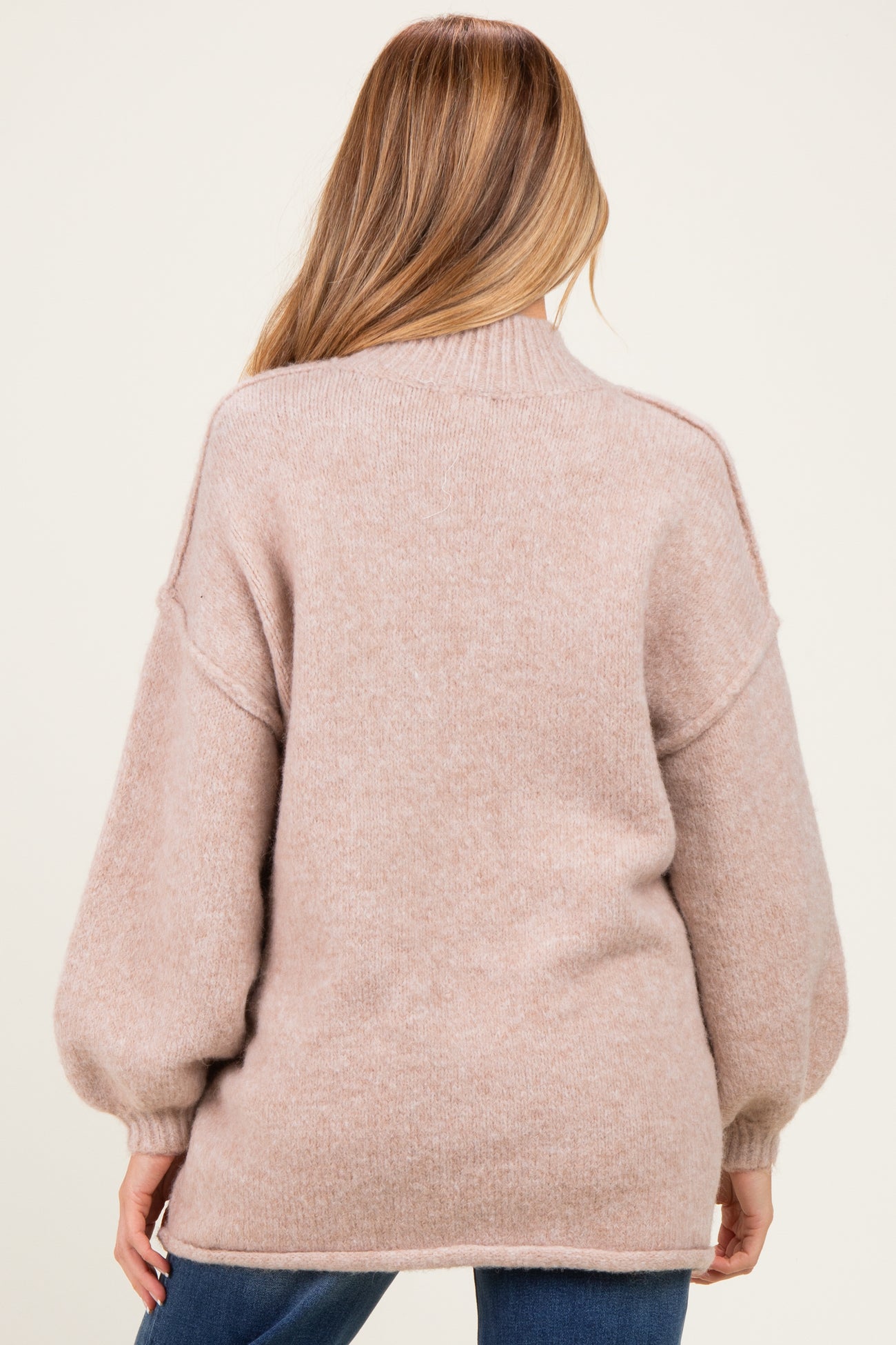 woman wearing a soft pink oversized maternity sweater with balloon sleeves, showing the back view