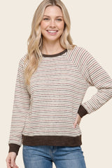woman wearing a striped cream and brown long sleeve sweater with a relaxed fit and ribbed cuffs