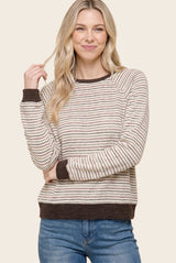 woman wearing a cream and brown striped long sleeve sweater with a relaxed fit and ribbed cuffs, smiling at the camera