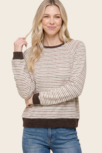 woman wearing a cream and brown striped long sleeve sweater with a relaxed fit and ribbed cuffs, smiling at the camera