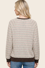 woman wearing a cream and brown striped sweater with raglan sleeves and a ribbed hem