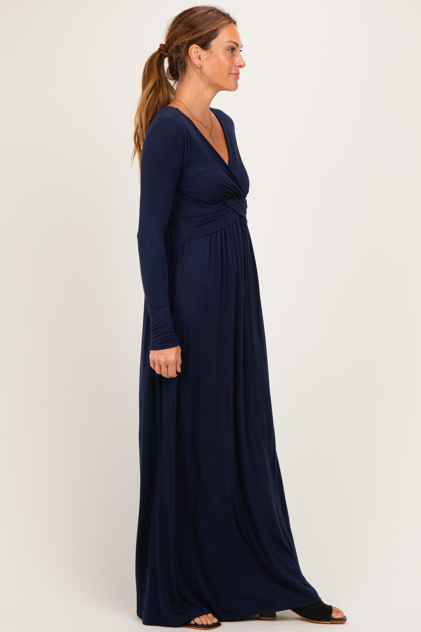 woman wearing a navy blue long sleeve maxi dress with a twisted bodice detail