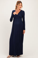 woman wearing a navy blue long sleeve maternity maxi dress with a wrap neckline and visible baby bump