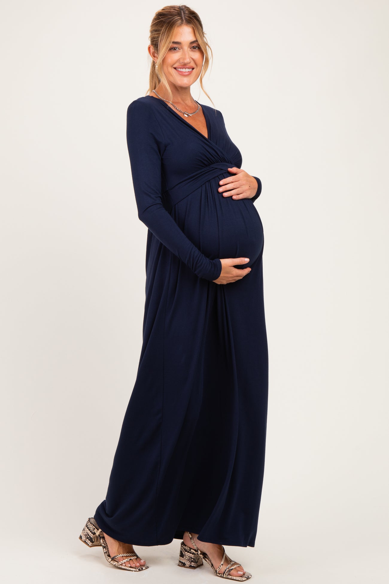 woman wearing a navy blue long sleeve maternity dress and holding her baby bump