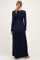 woman wearing a long sleeve navy blue maternity maxi dress with a fitted bodice and flowing skirt